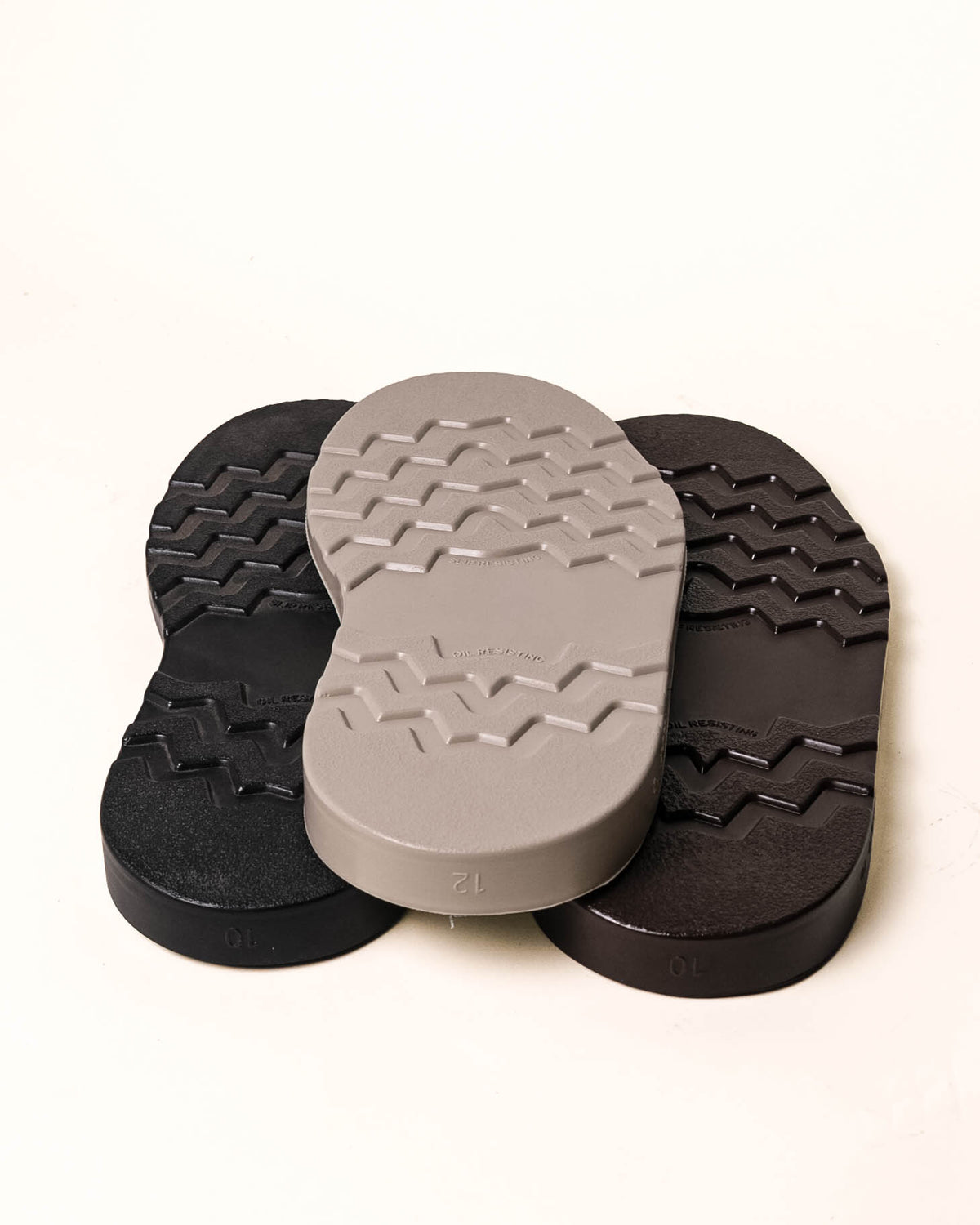 All three colors of wedge soles stacked in a pyramid with off white background. White wedge is on top with the black wedge lower left and the brown wedge lower right.
