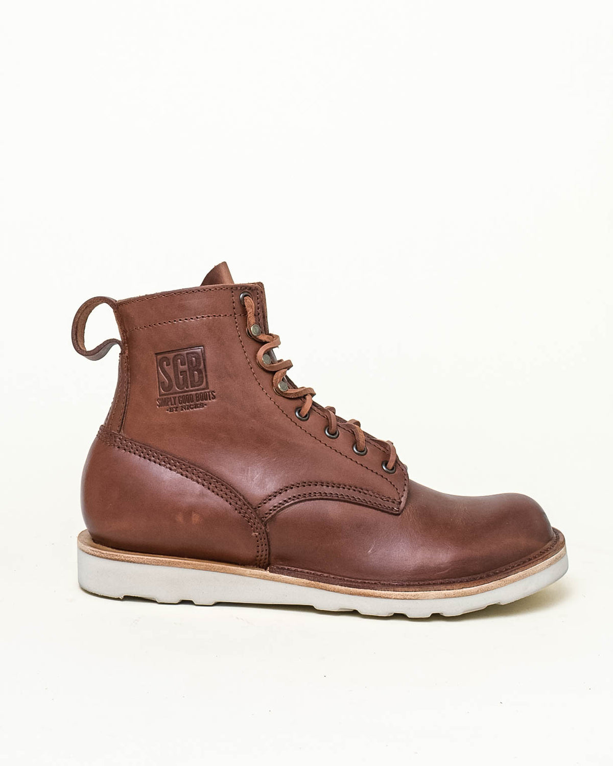 Brown leather ankle boot with white wedge sole. Boot shown in side profile in front of off white background. Stamp on upper of the boot reads 'SGB' with 'SIMPLY GOOD BOOTS BY NICKS' under.