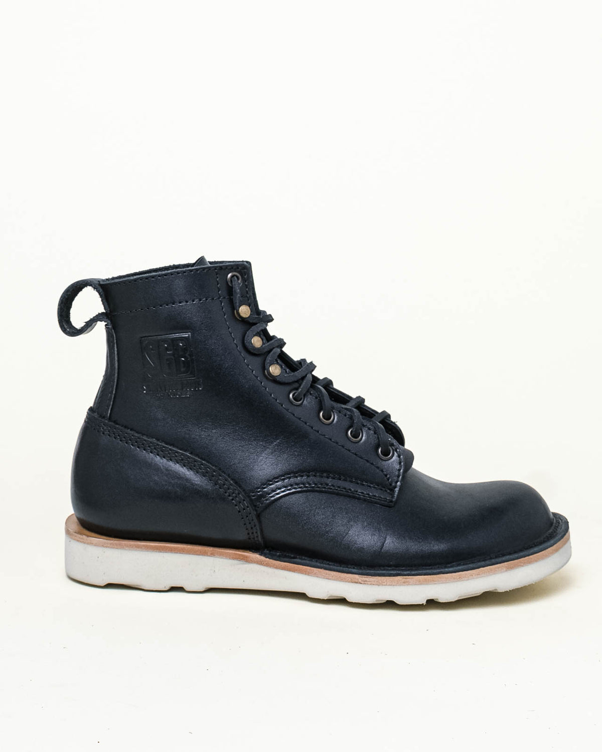 Black leather boots with white sole shown in side profile in front of off-white background. Stamp on boot upper reads 'SGB' with 'SIMPLY GOOD BOOTS BY NICKS' under. 